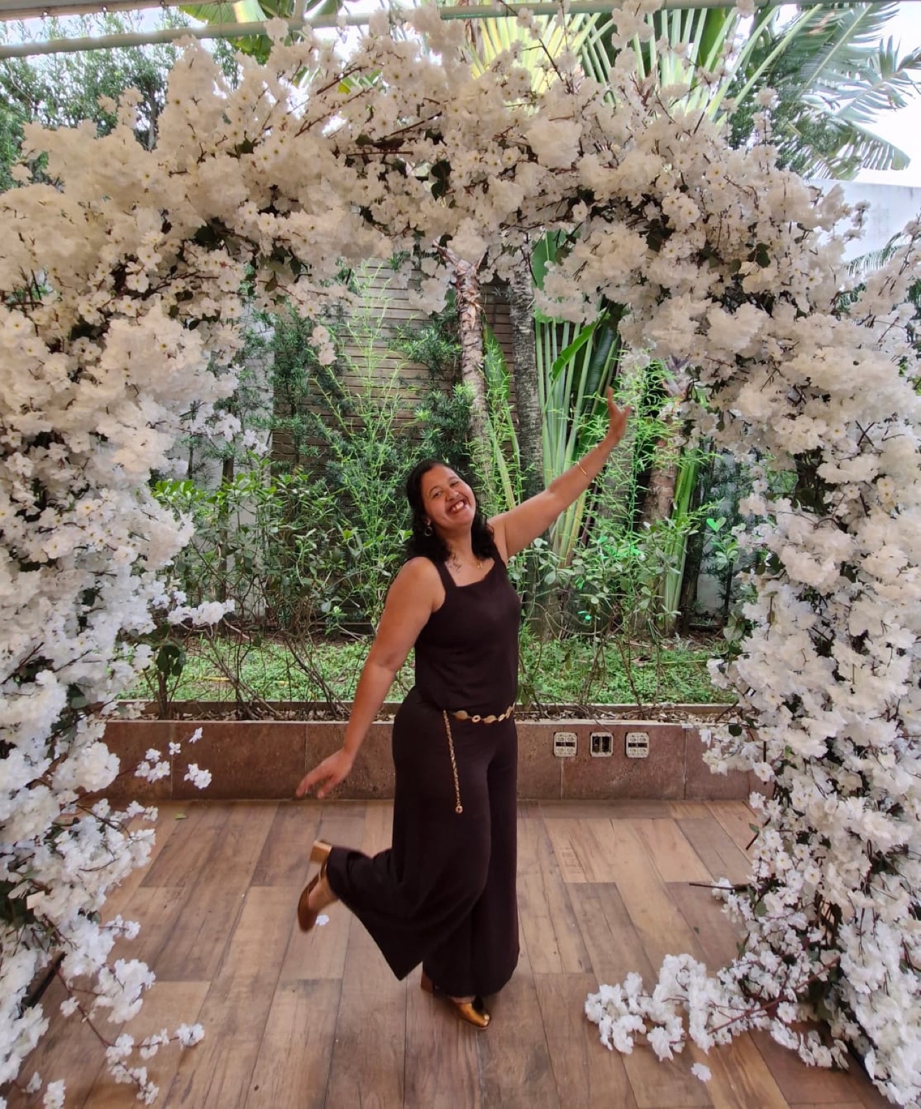 Priscilla Bento em pose de dança sob um arco de flores